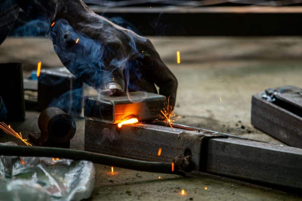 Worker handling glowing hot steel part during heat resistant metal casting